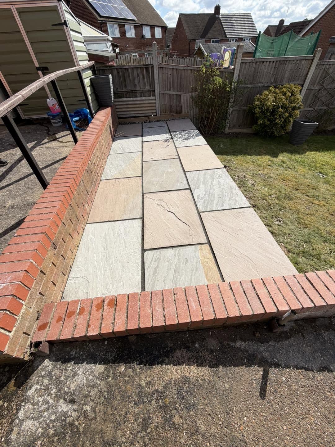 New sandstone path beside the same brick wall