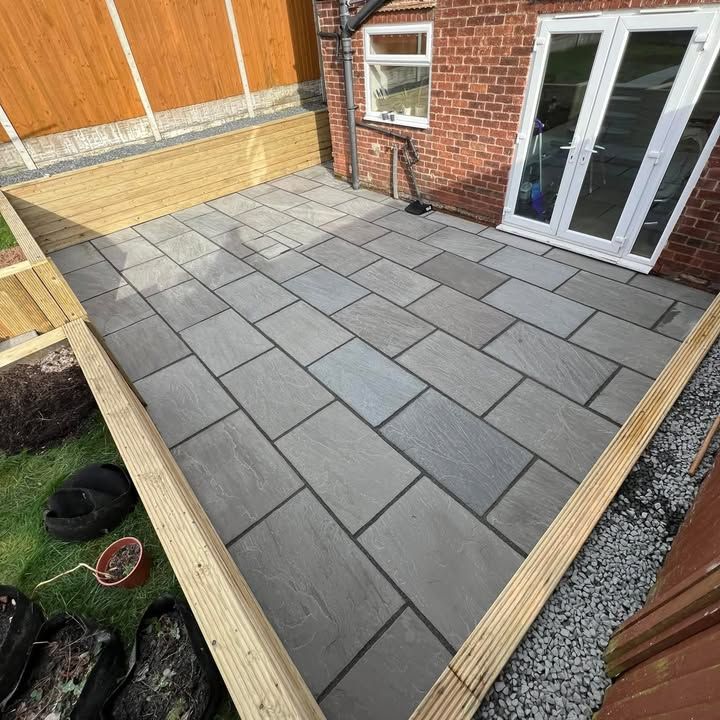 Grey slab patio with raised timber sleeper beds and slate chippings
