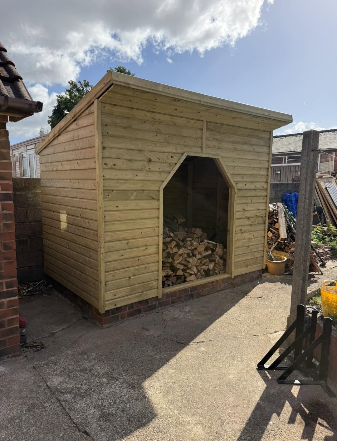 A timber log store with a pointed opening, stacked with logs
