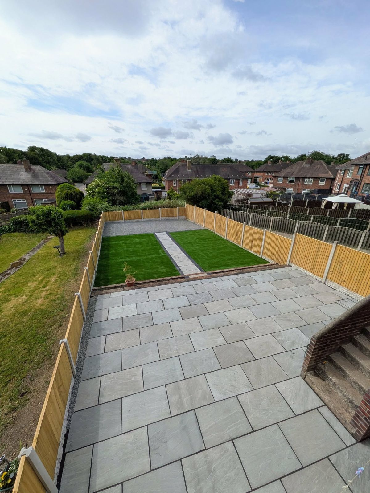The same garden with a new grey patio, new fencing and two strips of new lawn