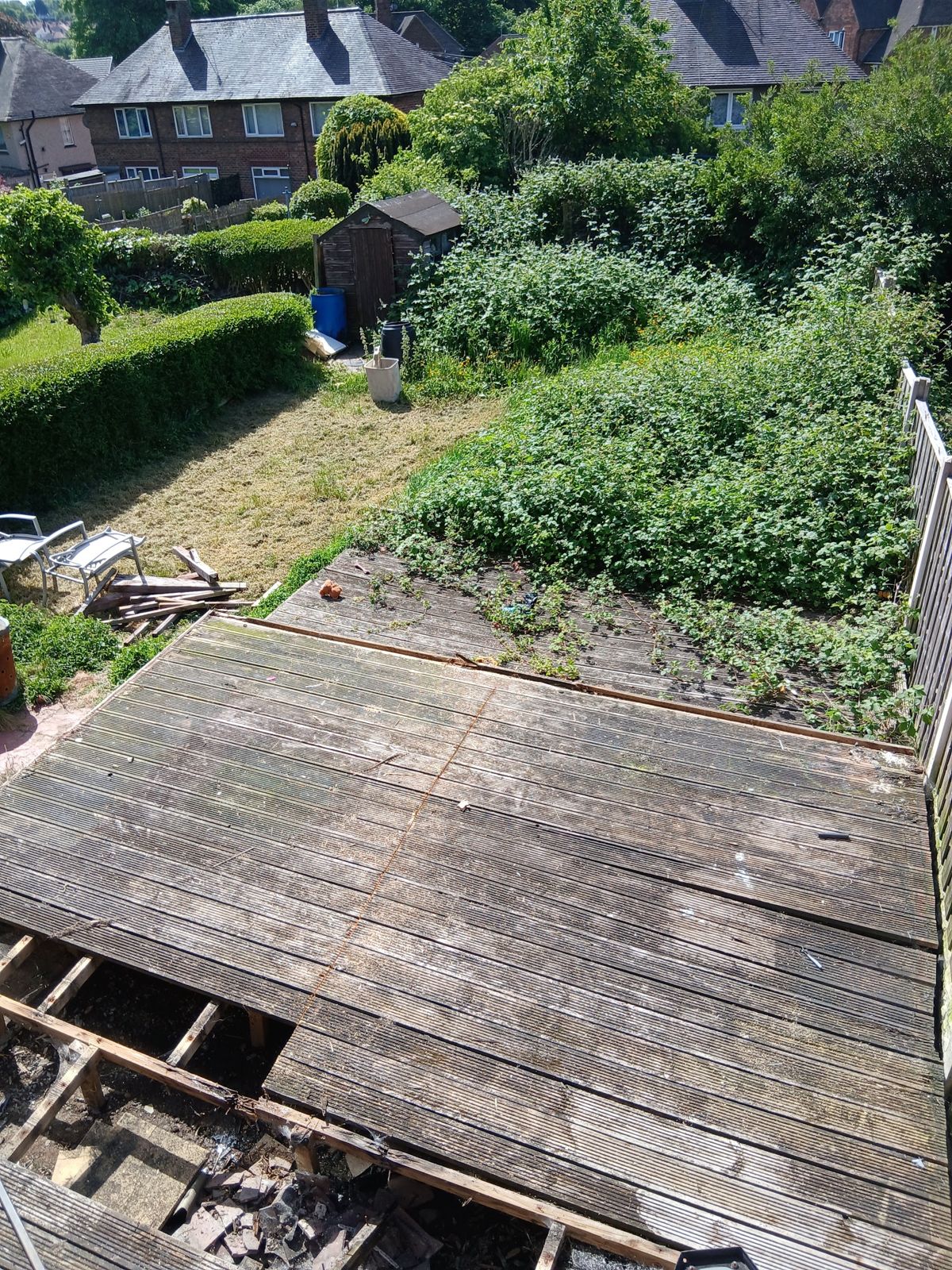 An overgrown garden with brambles and rotten timber decking