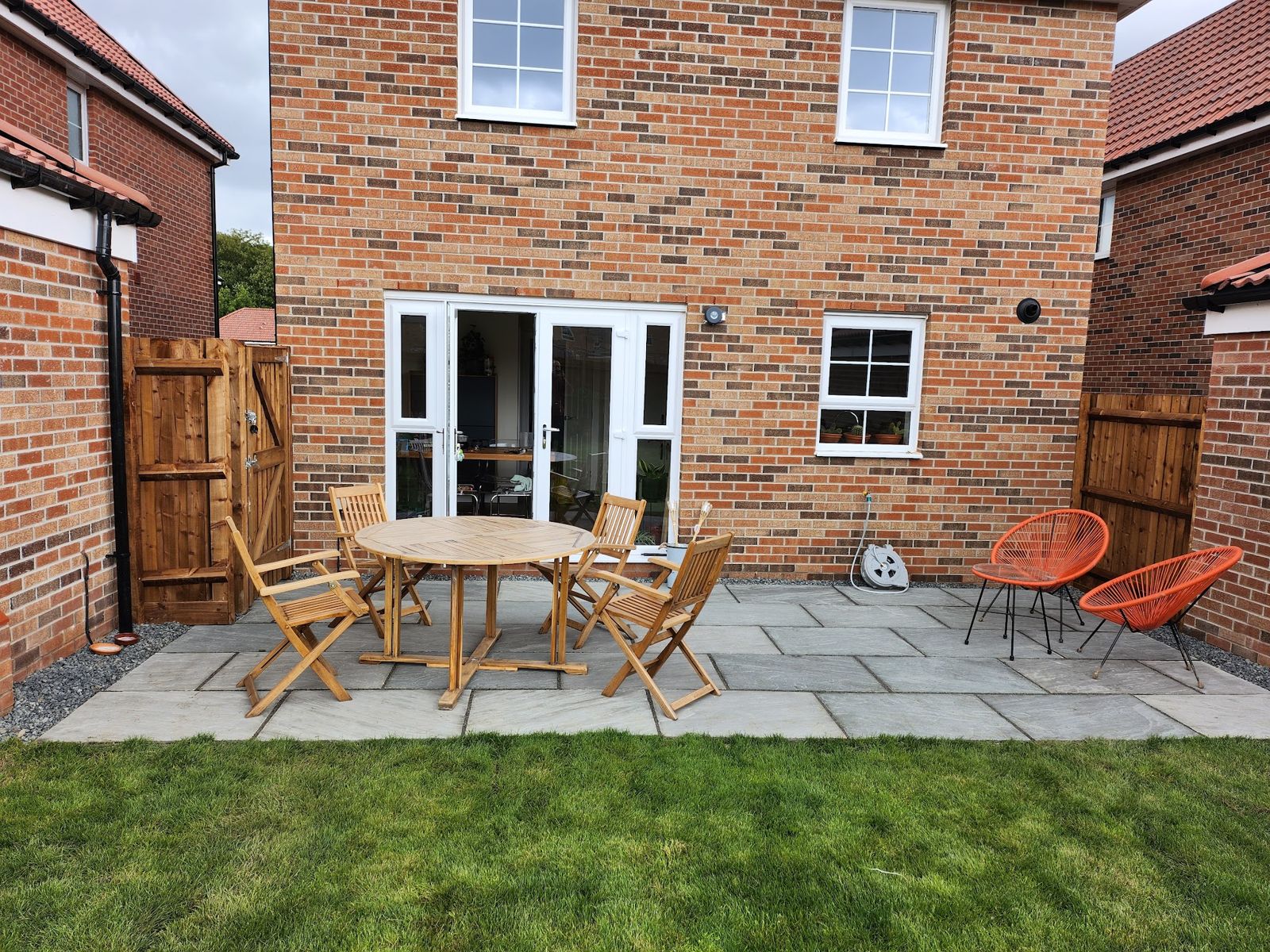 Grey patio with garden furniture behind a new-build house